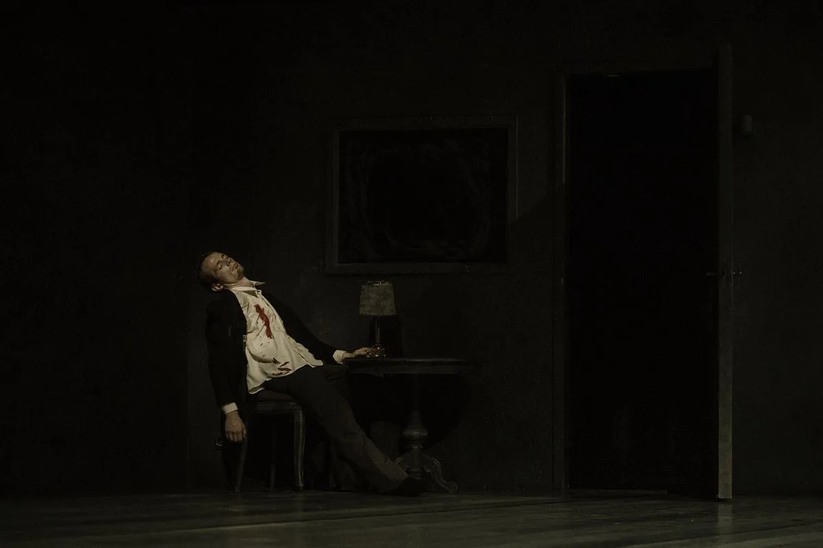 L'image est très sombre, on aperçoit seulement un danseur qui saigne, sa chemise est tachée de sang et il a les yeux fermés.