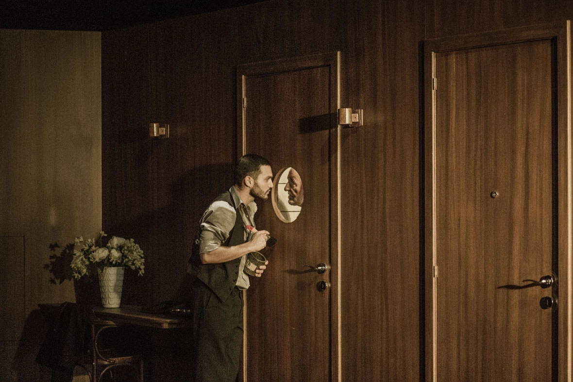 Deux danseurs se regardent à travers le hublot d'un porte. Le décors fait pensé à l'intérieur d'un bateau.
