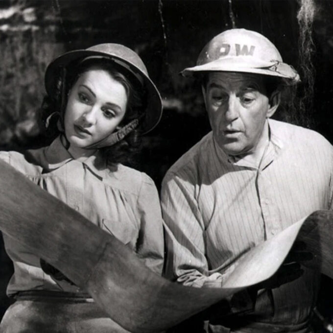 Les acteurs George Formby et Phyllis Calvert examinent une carte dans une scène du film britannique 